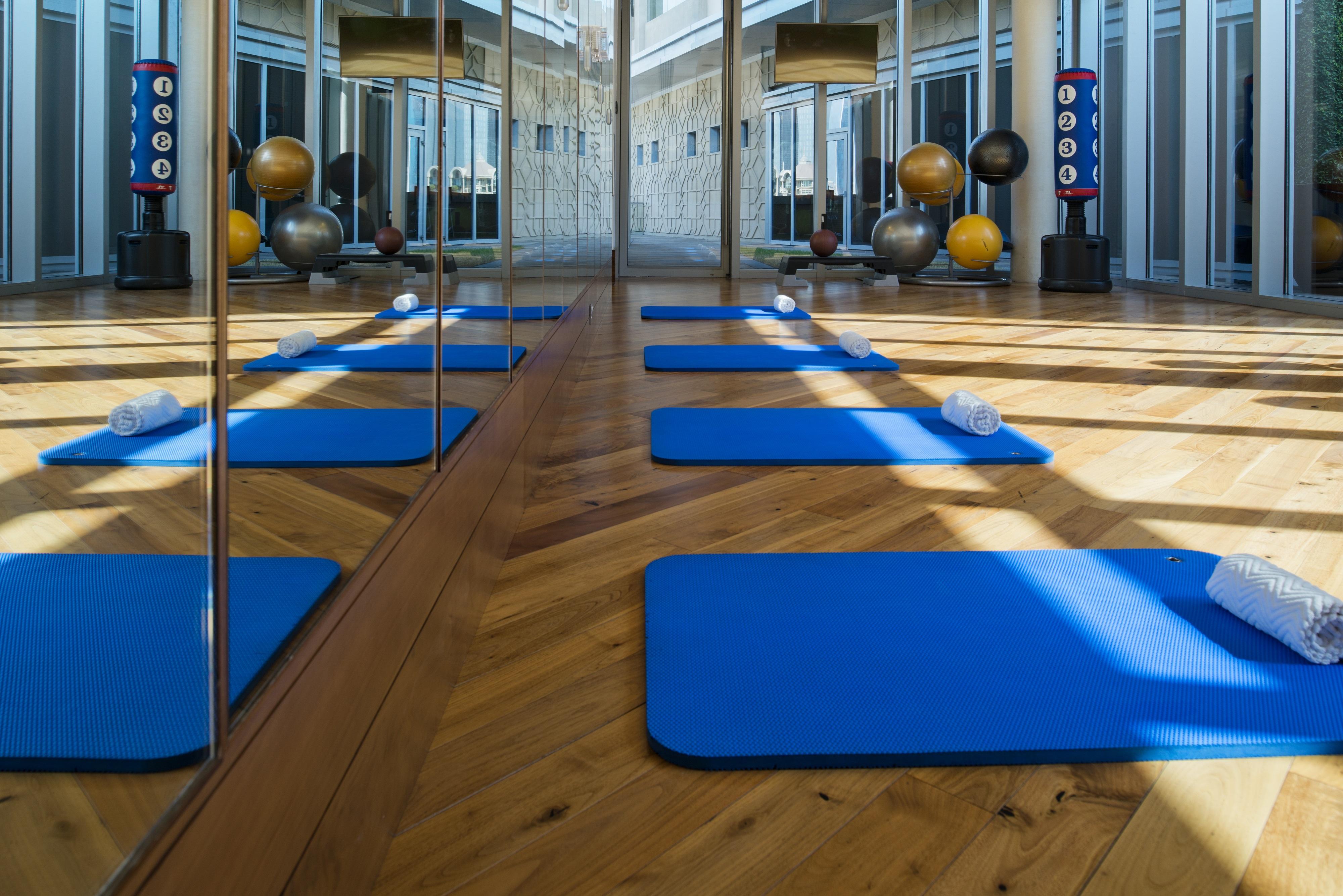 Kempinski Central Avenue Dubai Hotel Buitenkant foto The photo shows an interior space designed for exercise or yoga. There are several blue mats placed on a wooden floor, indicating areas for exercise or stretching. Mirrored walls enhance the openness of the space, and there are various exercise equip