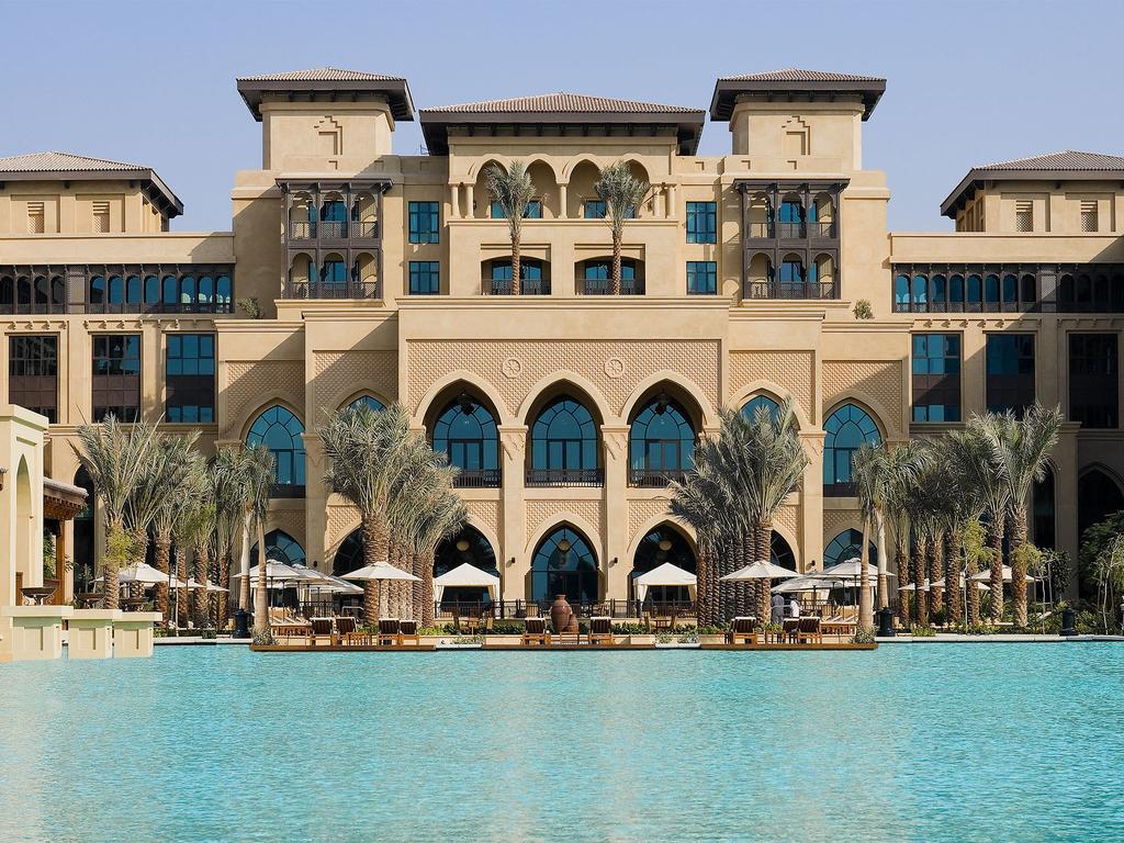 Kempinski Central Avenue Dubai Hotel Buitenkant foto The photo showcases a luxurious hotel or resort with a distinctive architectural style. The building features multiple levels, grand arches, and large windows, creating an elegant facade. In the foreground, there is a spacious swimming pool with a tu